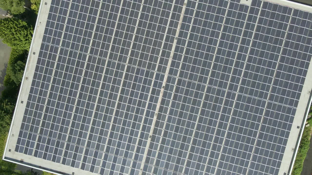 Ripresa aerea dall'alto di pannelli solari fotovoltaici su un tetto piatto - drone che si solleva e gira