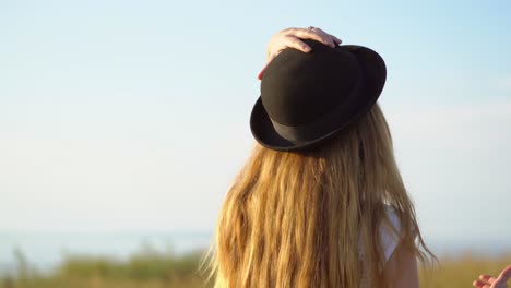 una mujer con un sombrero negro, contemplando una puesta de sol.