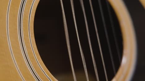 plucking the string of an acoustic guitar in slow motion over the sound hole