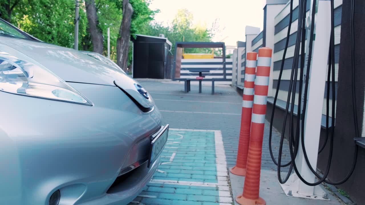 전기 자동차의 연료 충전 과정: 전기 에코 자동차가 충전하는 치 아래의. 전기 자동차 충전 치는 자동으로 열립니다. 남성 손이 발기 된 자동차를 입합니다.