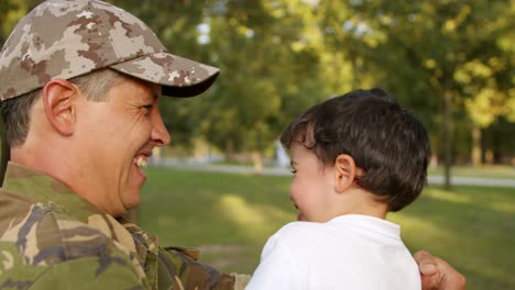 Happy-excited-dad-in-camouflage-holding-little-son-in-arms