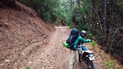 Mann-Klettert-In-Einer-Abgelegenen-Gegend-Im-Wald-Von-Seinem-Motorrad-Herunter---Halbtotale