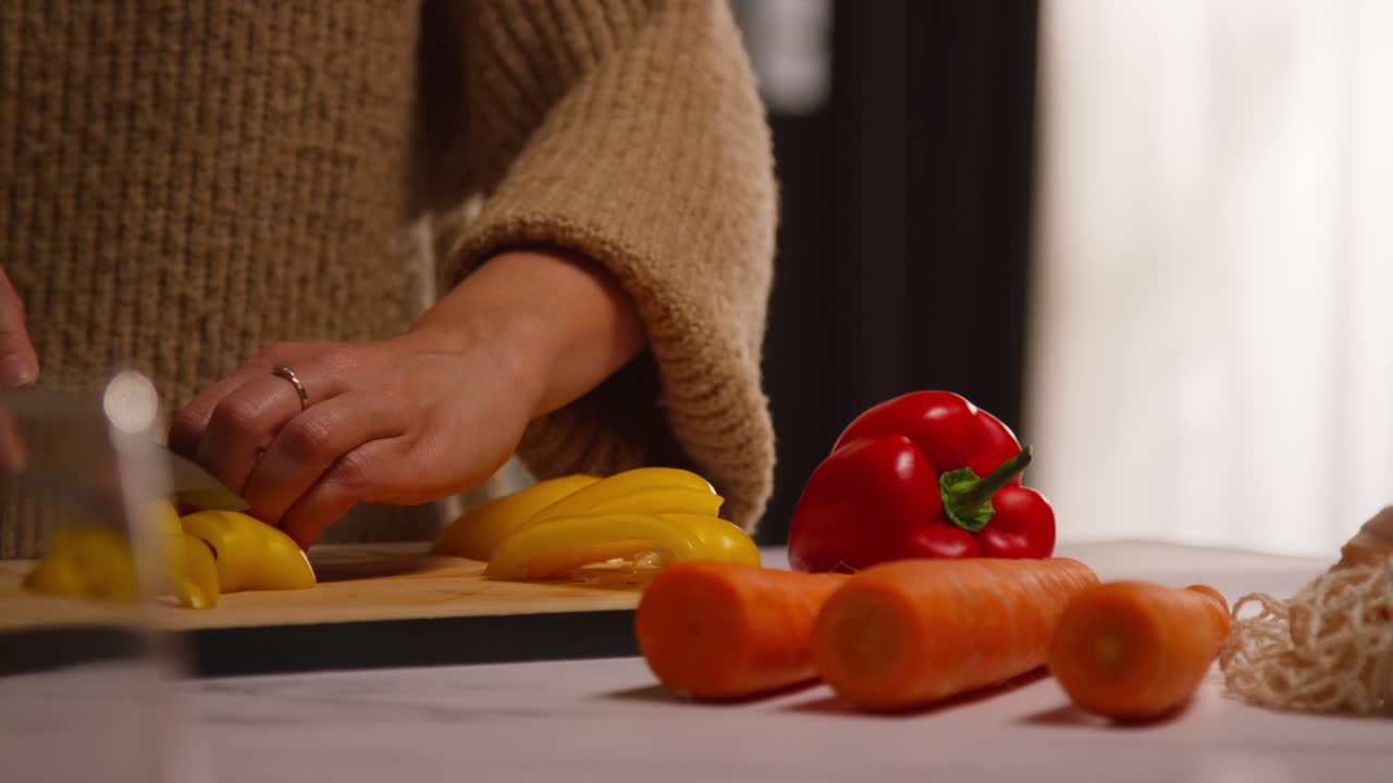 primer plano de una mujer en casa en la cocina preparando verduras frescas saludables para una comida vegetariana o vegana cortando pimienta amarilla a bordo 3