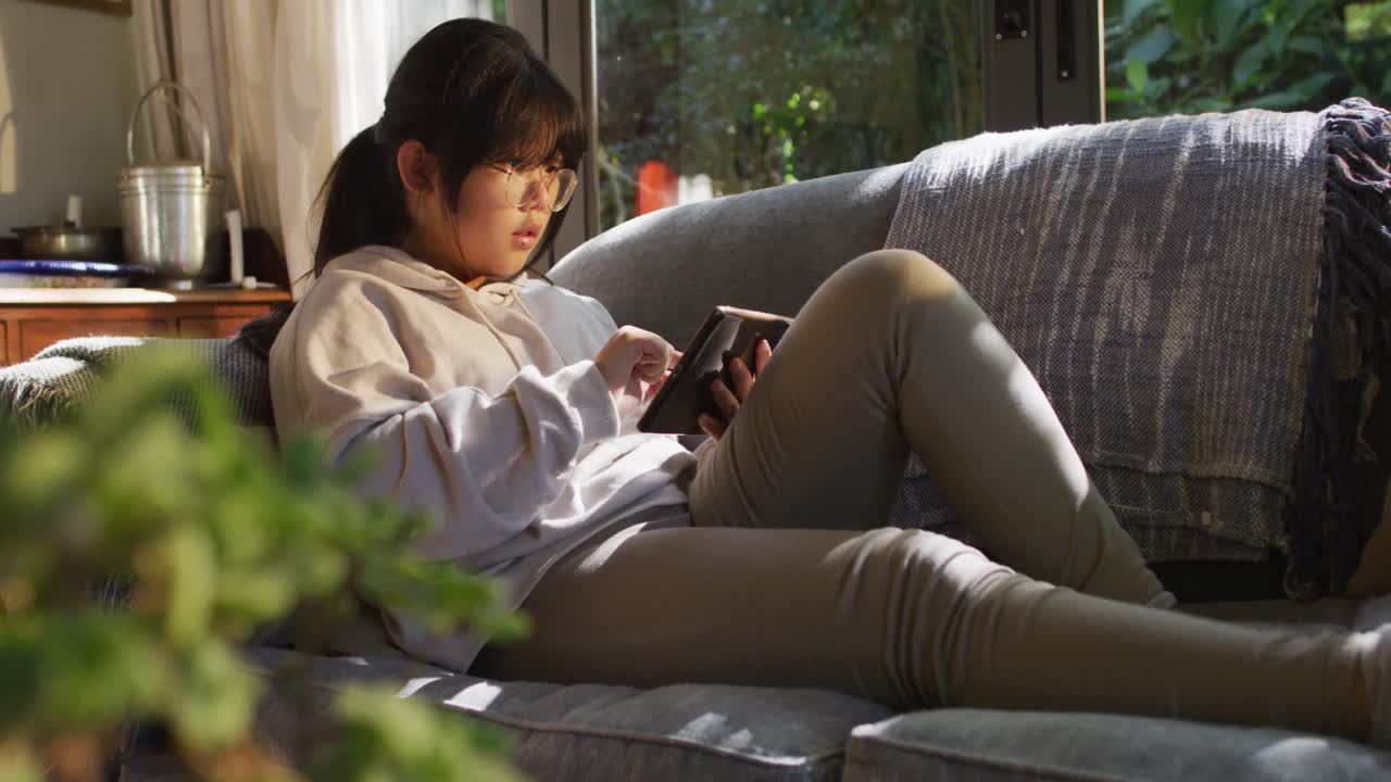 소파에 누워 태블릿을 사용하는 아시아 소녀