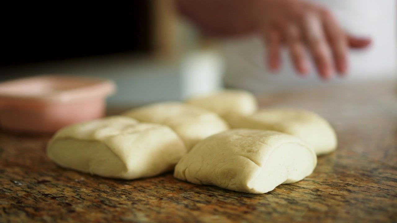 Filmato ravvicinato delle mani di uno chef che mettono l'impasto della pizza su un piano di lavoro dopo averlo tagliato.