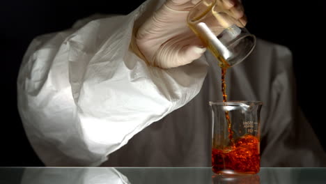 scientist pouring red liquid into beaker