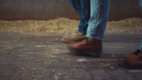 closeup livestock workers legs walking wooden shed. agricultural team at work.