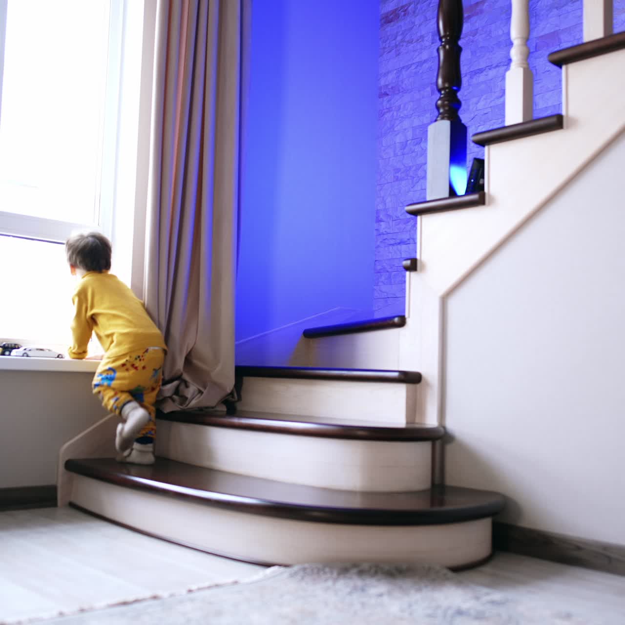 Adorabile bambino con abiti gialli che sale allegramente le scale. Il bambino carino guarda fuori dalla finestra.