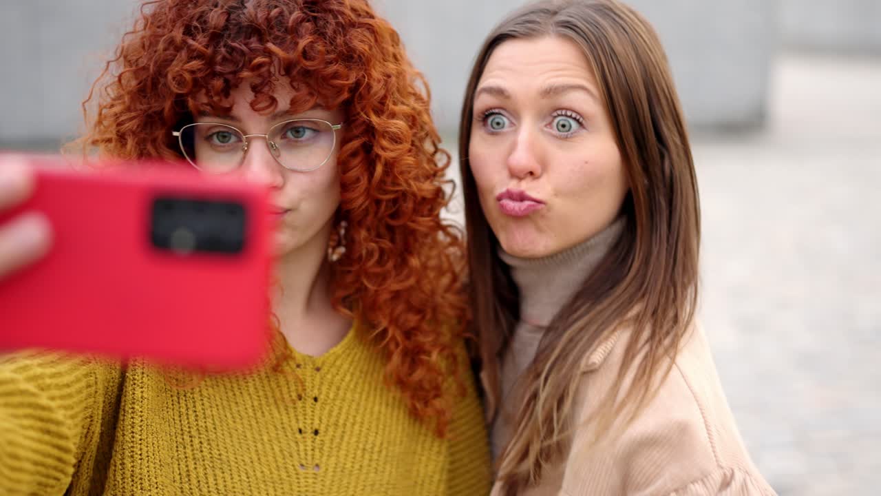 Female friends pulling faces taking a selfie outdoors