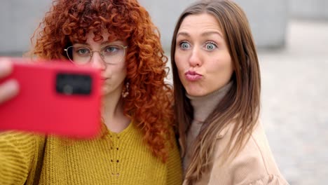 female friends pulling faces taking a selfie outdoors