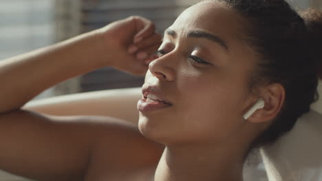 woman relaxing in a bath with earbuds