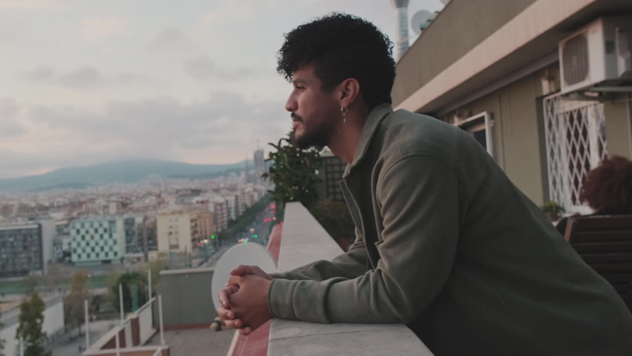 Gün batımında şehre bakan balkonda duran adam