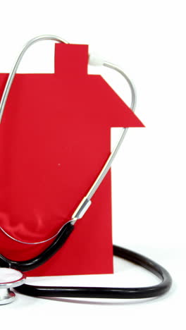 close-up of house model and stethoscope against white background