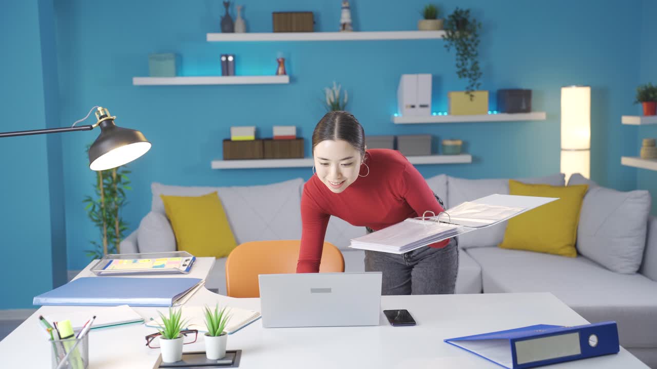 집에서 파일을 확인하는 아시아 여성은 노트북에서 보는 것에 만족합니다.