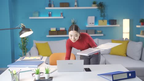 la mujer asiática que revisa archivos en casa está contenta con lo que ve en la computadora portátil.