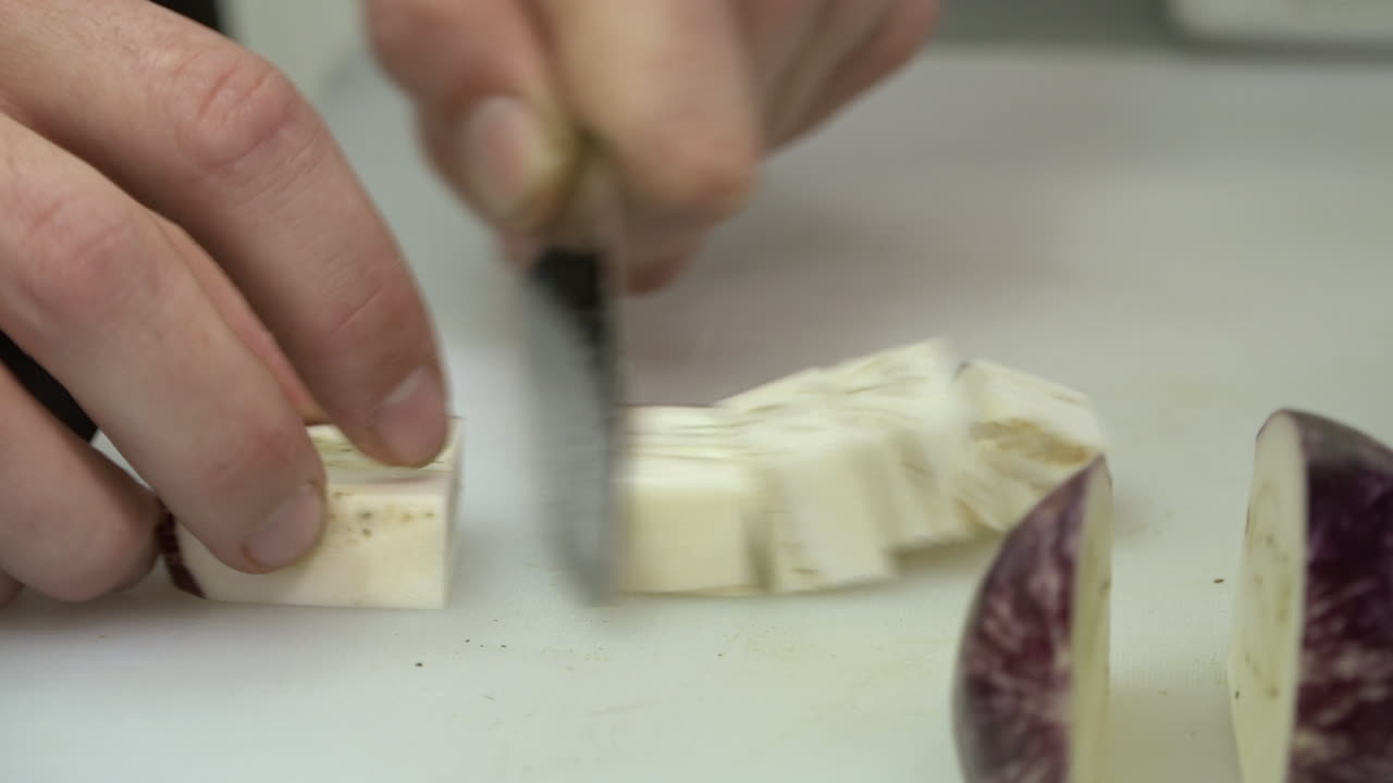 Close up of a chef dicing an eggplant
