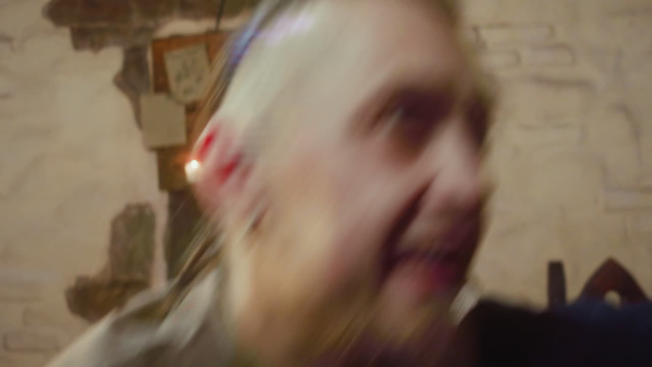 un alcohólico feliz cae en la silla bajo una mano pesada en la taberna. un hombre borracho con una sonrisa estúpida ve a un extraño interesante y trata de levantarse en una casa de huéspedes medieval