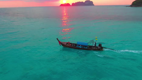 a low aerial view of a girl in longtail thai boat in sunset