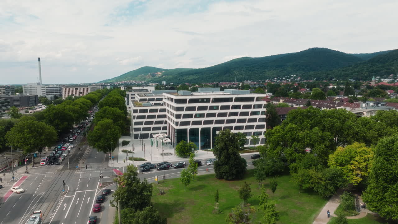 Panoramica laterale circolare con drone sopra un parco verso l'Ufficio Europeo dei Brevetti con tram e traffico