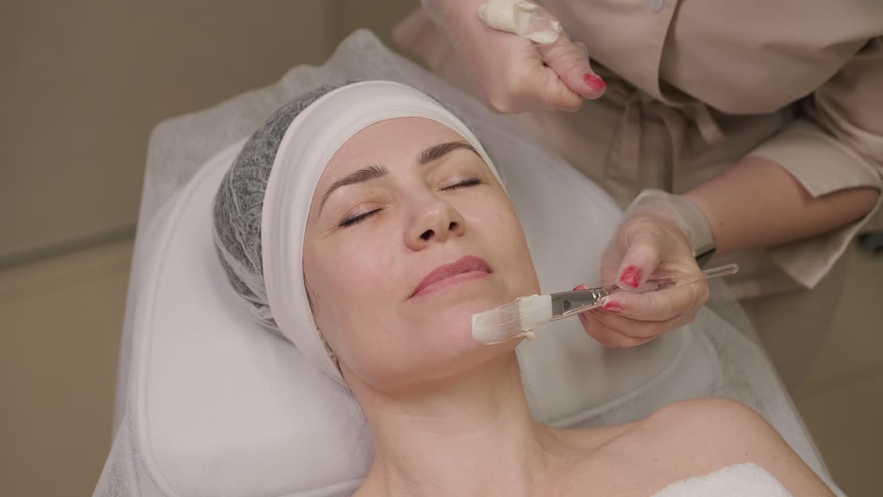 mujer hermosa con máscara facial en un salón de belleza