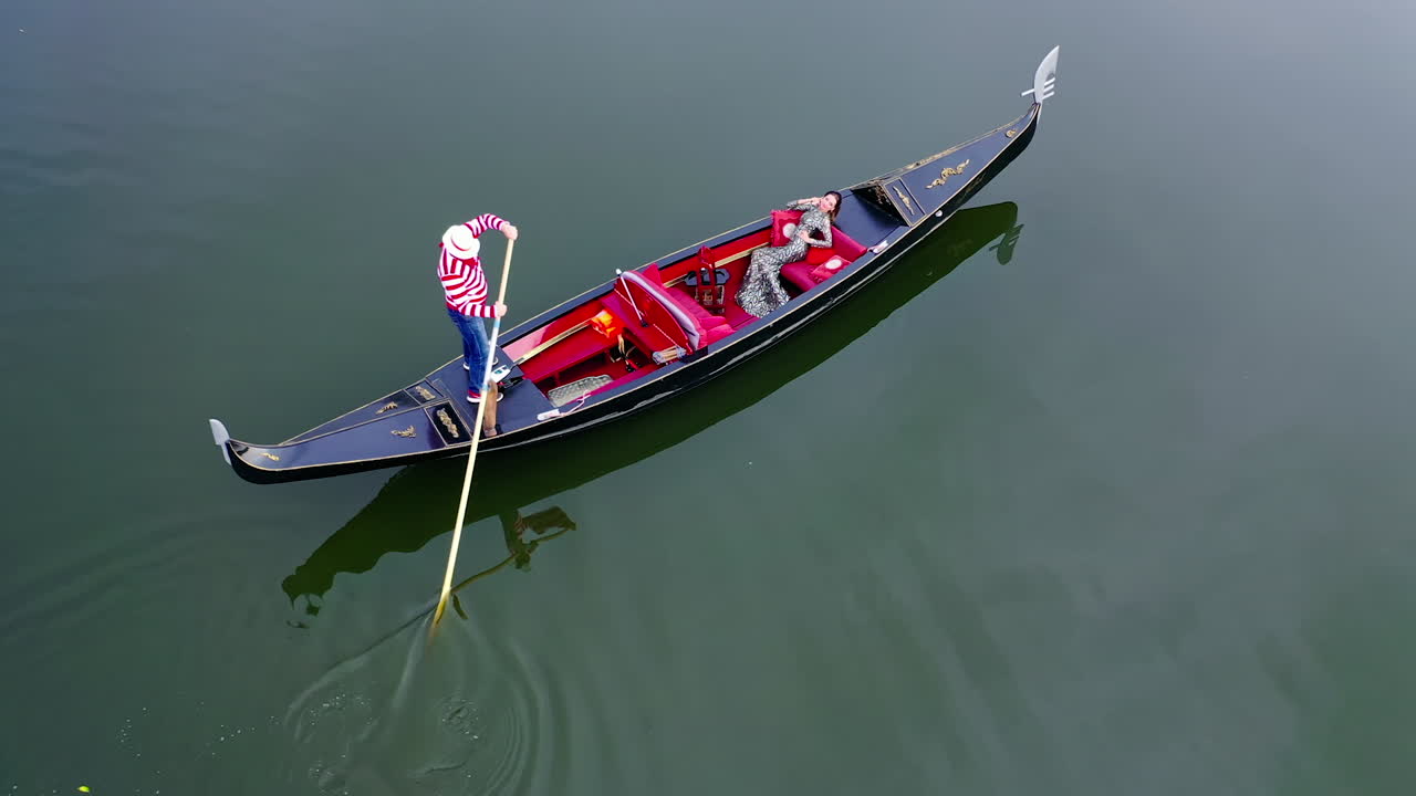 Gondolier putting gondola through river. Aerial view of gondolier carries tourists on gondola