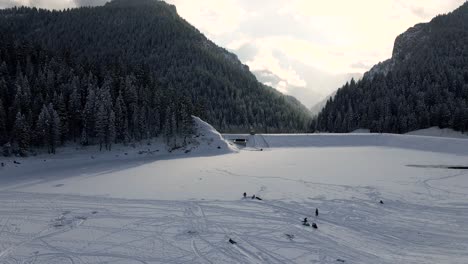 People-Sledding-on-Frozen-Tibble-Fork-Reservoir-in-American-Fork-Canyon,-Utah---Aerial