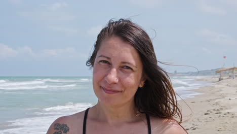 Close-up-Of-A-Woman-With-Long-Hair-Smiling-At-The-Camera-During-Summer-At-The-Beach---slow-motion