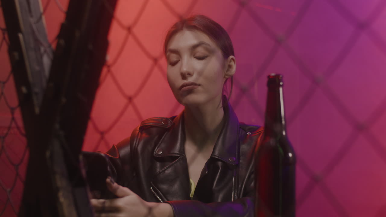 bella chica con chaqueta de cuero usando un teléfono móvil en la discoteca