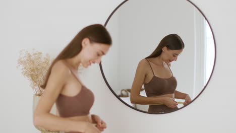 woman measuring her waist in front of a mirror