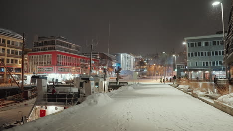 Slow-motion-night-shot-of-snowy-harbor-in-Tromso,-above-the-Arctic-Circle-in-Norway