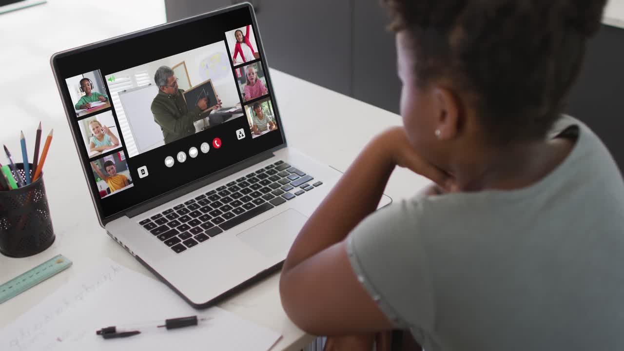 African american girl using laptop for video call, with male teacher and class on screen
