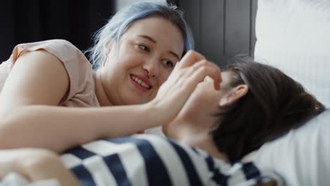 video of lesbian couple lovingly talking and kissing in bed.