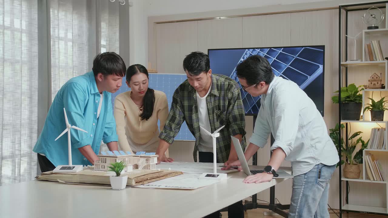 아시아 엔지니어 그룹은 태양 전지 패널 집 모델을 가지고 청사진을 열고 사무실에서 작업에 대해 논의합니다.