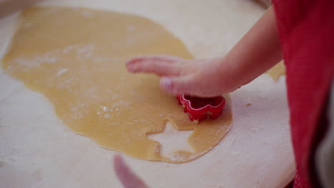 close up of a boy making gingerbread cookies and shaping them in the kitchen