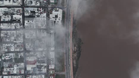 aerial top-down view of montevideo, featuring its iconic coastal boulevard (la rambla), busy streets with cars in motion, and clouds drifting gracefully across the urban landscape