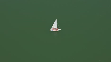 sailboat sailing on green water on sunny day. crew and passengers on board ship. aerial view. andalusia. spain.