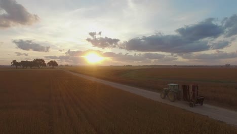 Granjero-Conduciendo-Grandes-Equipos-Agrícolas-Comerciales-Industriales-A-Lo-Largo-De-Un-Camino-De-Tierra-Al-Amanecer