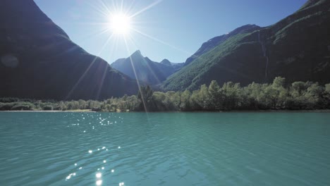 A-picturesque-landscape-of-a-serene-lake-and-mountains,-bathed-in-bright-sunlight