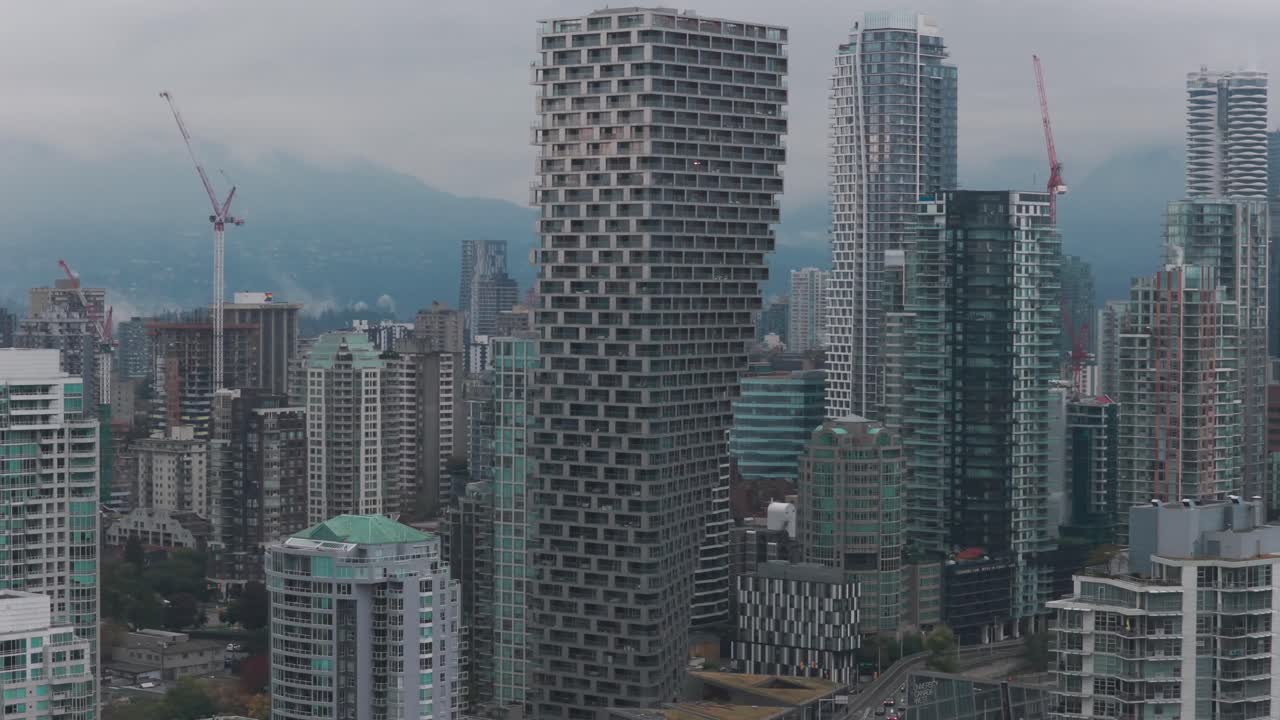 Telephoto panning aerial shot of the unique skyscraper Vancouver House architecture on a rainy afternoon in British Columbia, Canada. 4K