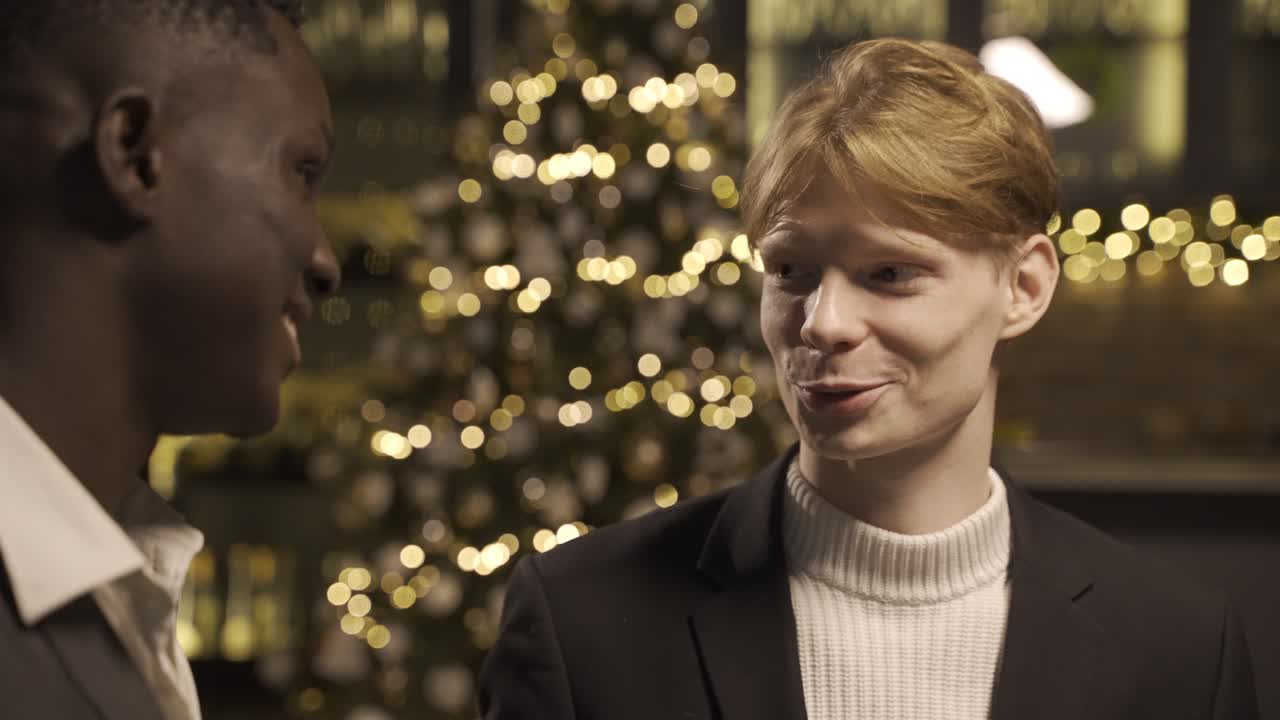 Close-up view of two friends wearing stylish clothes while talking and holding champagne glasses at new year's party