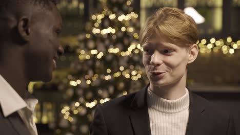 close-up view of two friends wearing stylish clothes while talking and holding champagne glasses at new year's party