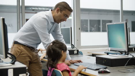 girl typing on keyboard for first time with help of teacher