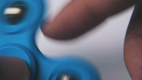 man plays with bright blue spinner on light background