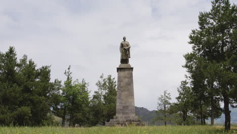 estatua de shota rustaveli sobre pedestal de piedra en el campo georgiano