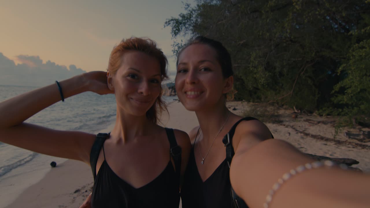 Two friends taking a selfie on a beautiful beach at sunset