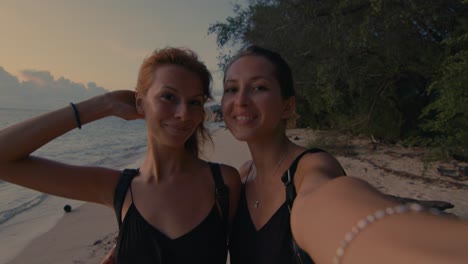 two friends taking a selfie on a beautiful beach at sunset