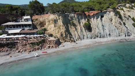 aerial dolly back view from seaside cliff above sol den serra beach in ibiza