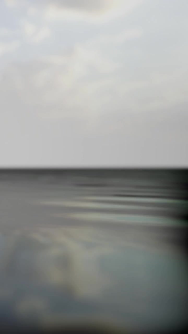 Waterscape view with horizon and cloudy sky during evening light hours
