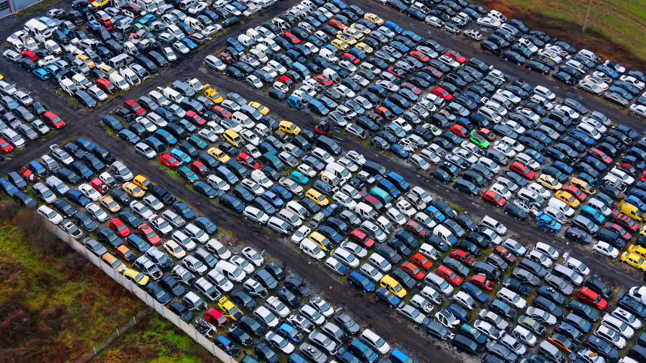 Luftfoto af stor bilkirkegård med rækker af gamle biler. Højt vinkelbillede af talrige skrotkøretøjer parkeret i organiserede rækker på et genbrugsanlæg