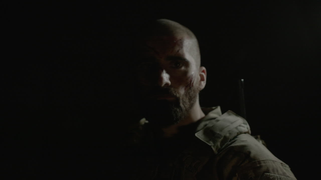 샷건을 들고 얼굴에 긁힌 자국이 있는 남자의 앞모습